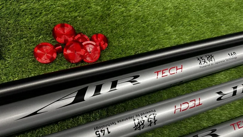 Daiwa Air Tech pole sections on grass beside a set of red Fox Worx pole bungs
